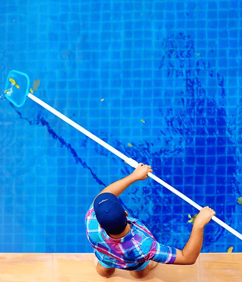 Pool Envy Pic 1 - A Pool Envy technician cleaning leaves from a swimming pool showcasing professional pool cleaning services