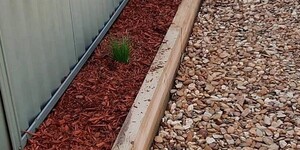 Daniel James Services Pic 4 - A retaining wall with decorative mulch and river stones