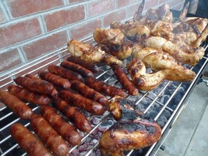 BBQ Spit Rotisseries Pic 3 - Sausages and chicken wings cooked on a charcoal BBQ