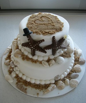 Brisbane Wedding Cakes Pic 4 - Beach themed wedding cake with a handmade cake topperstarfish with a top hat and flower Hand drawn heart and sea shels