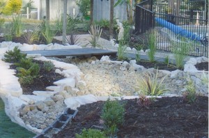 LCC Landscaping Pic 4 - natural rock fall with foot bridge