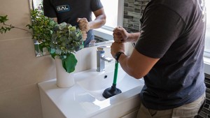 JAB PLUMBING SOLUTIONS Pic 4 - Drainage professional clearing a blocked bathroom sink using hand held plunger