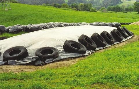 SilageCovers1 Pic 1 - A silage pit covered with a durable plastic sheet secured by tires to protect livestock feed from UV degradation in a grassy rural area